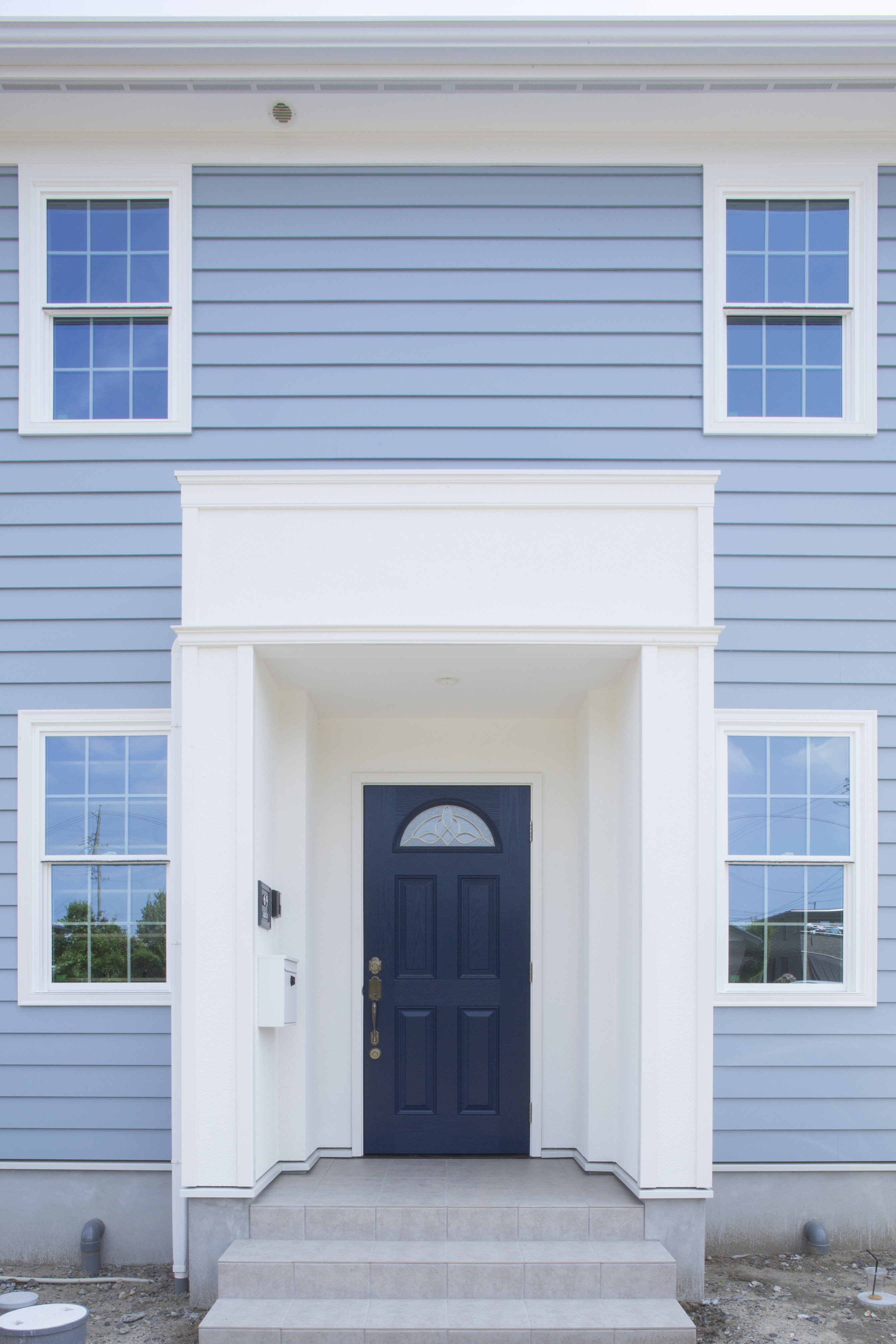 ブルーのサイディングと紺色の玄関ドア